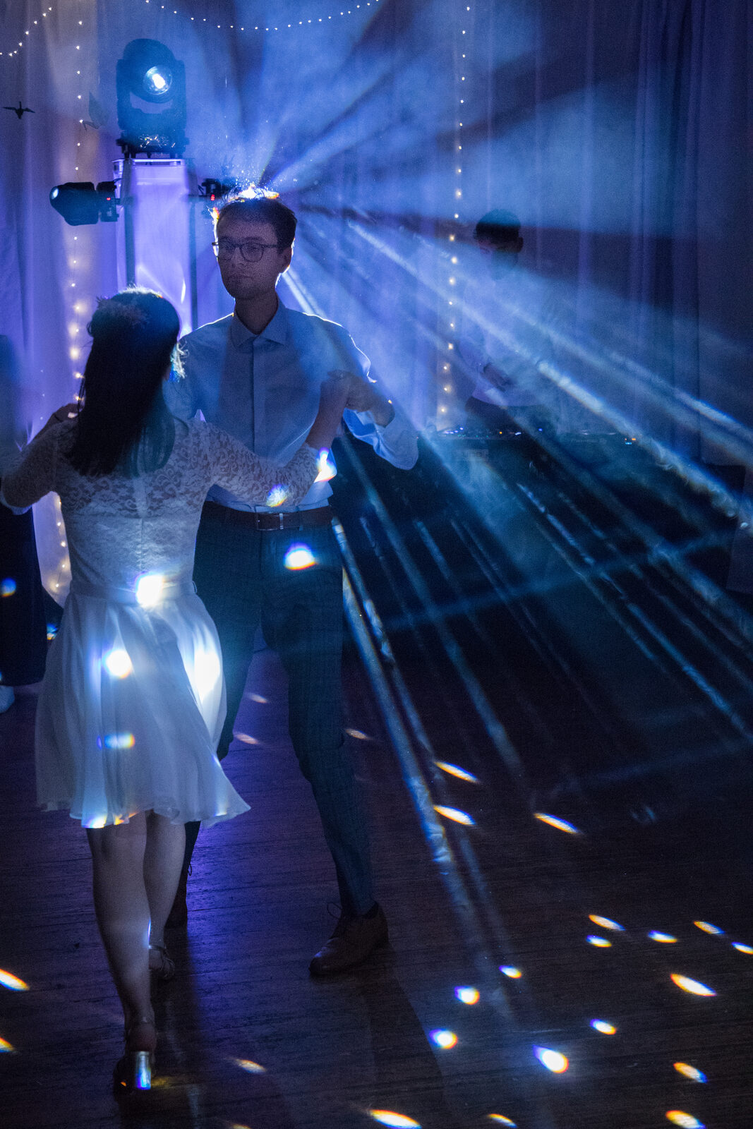 Couple dansant sous les lumières lors d'un mariage